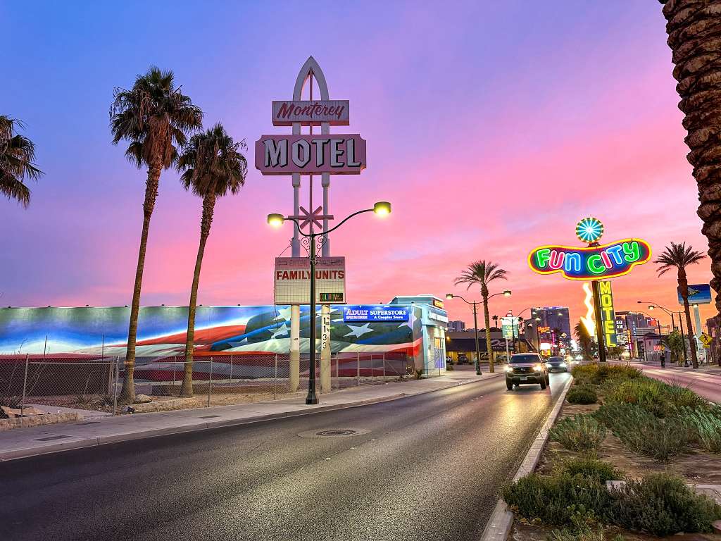 Vintage motel signs glowing at sunset on a palm lined street